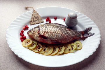 Fresh fish on a white plate with quince slices and a Christmas tree, side view-the concept of preparing fish dishes for a festive new year's table