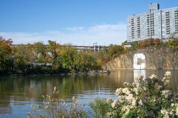 Obraz premium Apartment complex building built on a rock cliff with the letter C, with a view of creek and Inwood Hill Park