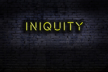 Neon sign. Word iniquity against brick wall. Night view