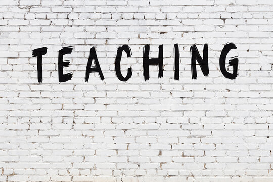 Inscription teaching painted on white brick wall