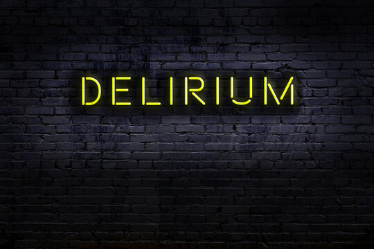 Neon sign. Word delirium against brick wall. Night view