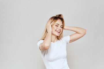 cheerful blonde in a white t-shirt gesturing with her hands light background