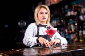 Girl barman formulates a cocktail in the taproom