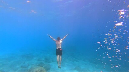One young man diving towards the surface from the sea floor