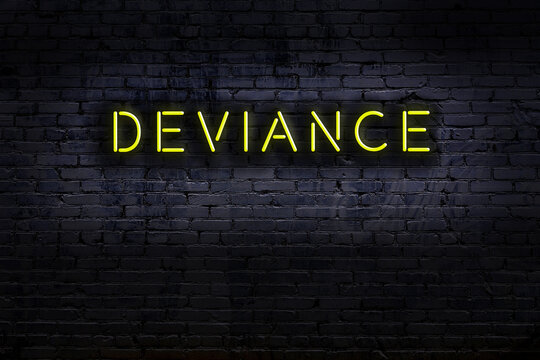 Night view of neon sign on brick wall with inscription deviance