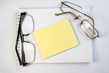 on a white background, along with a Notepad is a sheet of notes among two broken old eyeglasses.