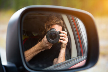 Handsome young traveler photographer taking photo from the car while driving on road trip. Concept about lifestyle, travel and people.