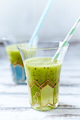 Green smoothie on bright wooden background. Close up. 