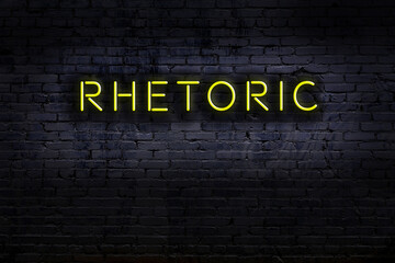 Night view of neon sign on brick wall with inscription rhetoric