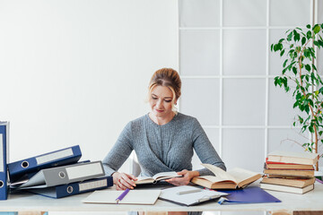 beautiful woman in business suit at a table with folders and papers in the office