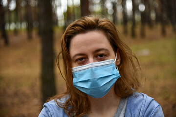 Young woman wearing in a protective mask in a park. Quarantine, anti coronavirus, virus and flu concept.