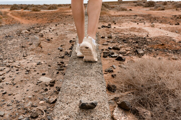 Close-up of feet walking on top of a wall.