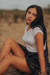 A photo session with a young lady dressed in black in nature, in the background is a brown chain