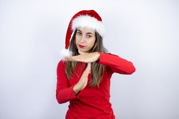Young beautiful woman wearing a Santa hat over white background Doing time out gesture with hands,...