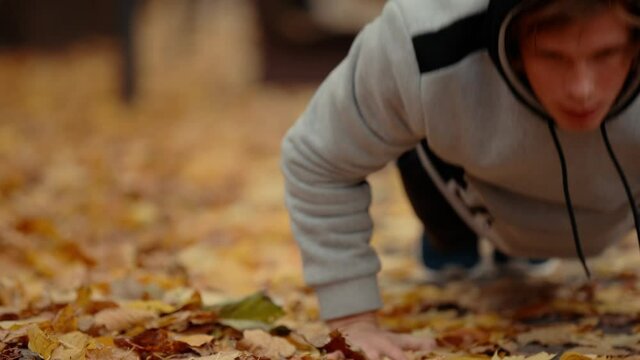 Man pushups outdoor at the autumn park making his muscles more stronger