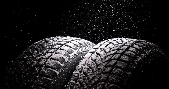 Winter car tires and snow rain on black background, 4K slow motion video