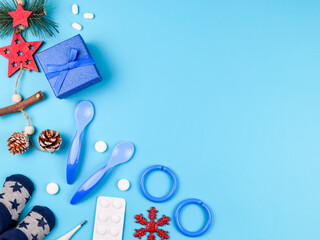 socks, gift and baby accessories.
socks, gift, pills, spoons and christmas decor on a blue background on the left with a place for text on the right, top view close-up