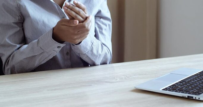 Close up female hands of african american woman with dark skin, girl office worker treats palms with antiseptic sanitizer typing on laptop, freelancer lady uses alcoholic liquid gel to fight bacteria