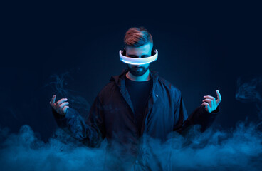 Young man on dark virtual reality background. Guy using VR helmet. Augmented reality, future...