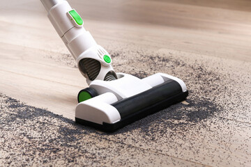 A man uses a bagless vertical cordless vacuum cleaner to clean the floor.