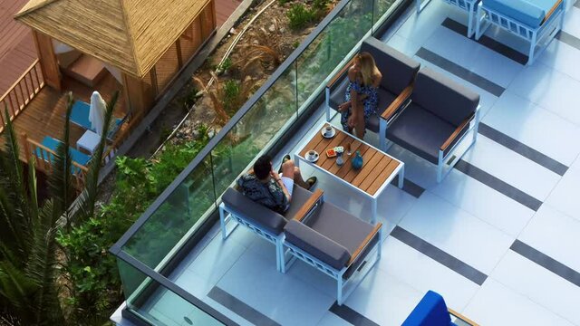 couple drinking coffee on the hotel's terrace with sea view, taken by drone.
