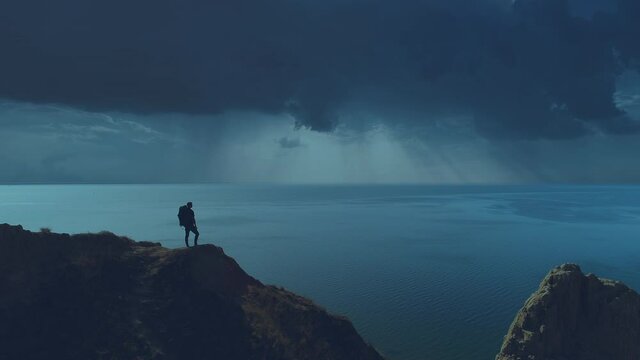 The tourist is standing on the mountain cliff on the night seascape background