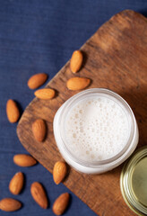 Overhead view of almond milk with whole almonds on a rustic cutting board, copy space