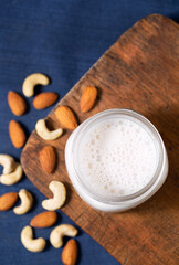 Overhead view of nut milk with whole almonds and cashews with copy space