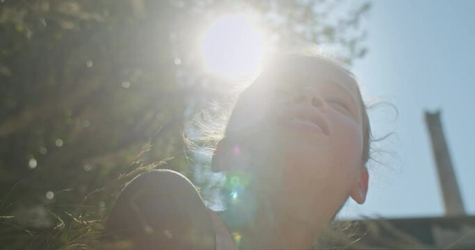 Close up of a young cute teenage girl sitting in the grasslooking up, on a sunny day in an old european town