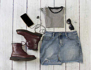 Still life of clothes, denim mini skirt, striped shirt, hat, smartphone and headphones