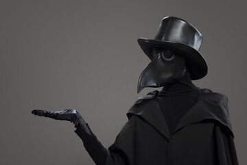 The plague doctor points to a gray background. - 392149748