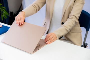 定時なので業務を終わらせノートPCを閉める女性【2020】