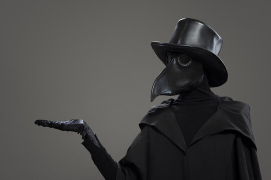 The plague doctor points to a gray background.