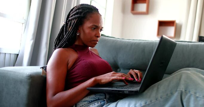 African black woman typing on laptop computer at home