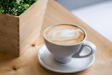 morning cup of latte in a white bowl on a wooden table on the coffeeshop