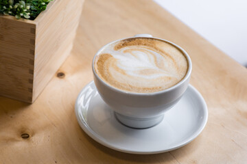 morning cup of latte in a white bowl on a wooden table on the coffeeshop