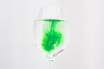 A drop of green liquid was just poured into a clear wineglass