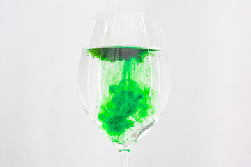 A drop of green liquid was just poured into a clear wineglass