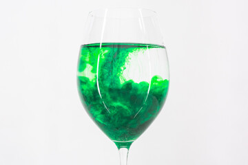 A drop of green liquid was just poured into a clear wineglass