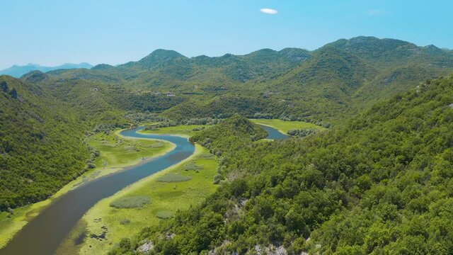Aerial view of the the old Rijeka Crnojevica river, surrounded by picturesque green trees 