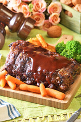 Grilled and smoked pork ribs with barbeque sauce on a wooden board. 