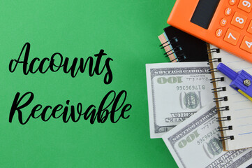 Top view of banknotes, notebooks, pen and calculator on a green background written with text ACCOUNTS RECEIVABLES. Business and financial concept. Selective focus.