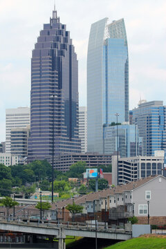 The contrast of small family home towns in front of  huge office buildings. 