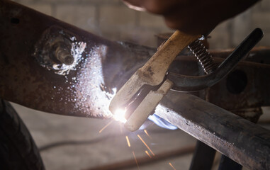 Welding Man Welding Construction of Car in Garage on Center Frame in Zoom View