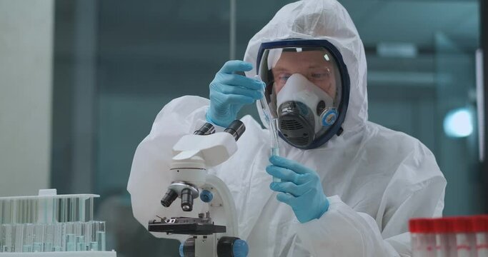 virologist is researching danger virus in laboratory, man is dressed protective overall and face mask with respirator, developing