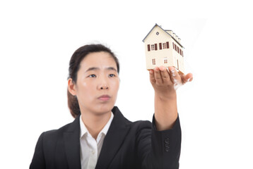 Young female salesperson in formal wear holding small house model in front of white background