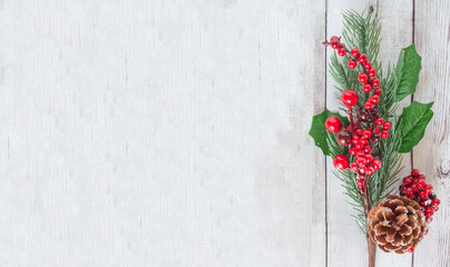 Christmas tree branch with decorations on a white wooden table, top view