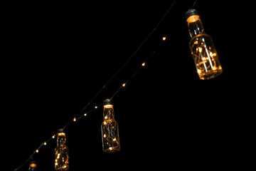 Small bottle shaped lamps hanging at night with black background