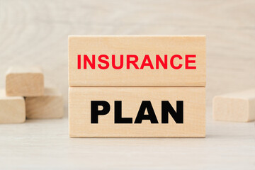 the word PLAN INSURANCE is written on a wooden cubes structure. Cube on a bright background. Can be used for business, marketing, financiaL, INSURANCE concept. Selective focus.