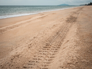 Perspective of car tire tracks on tropical sandy beach. copy space provided.